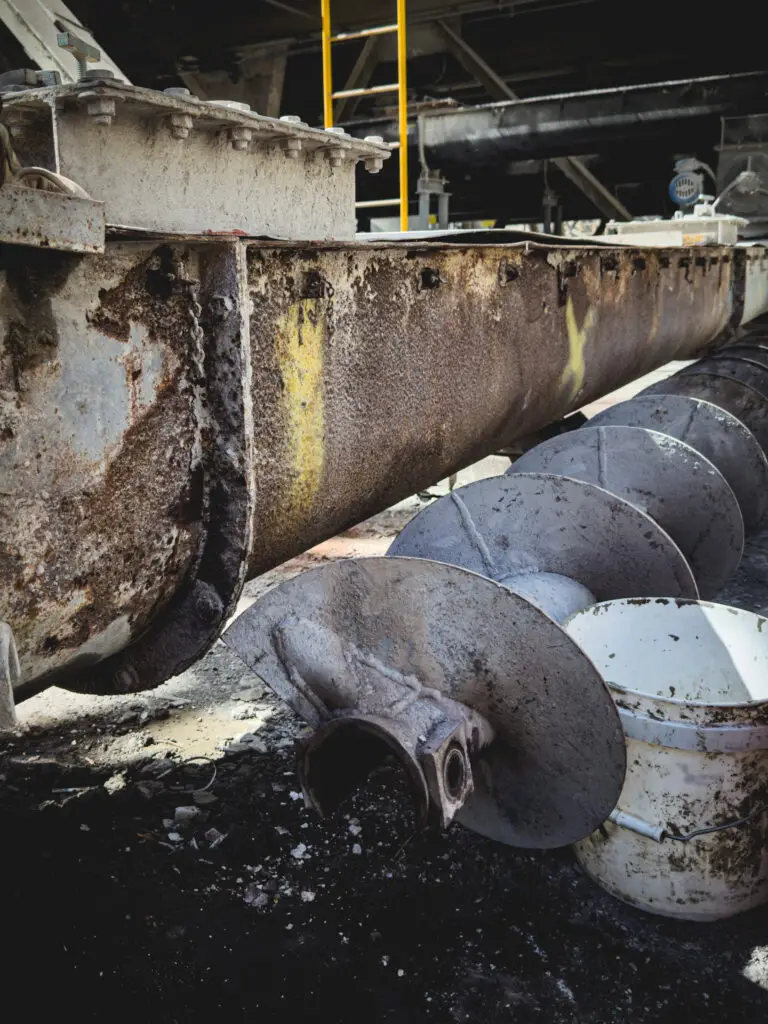 Damaged screw conveyor in need of repair in industrial setting.