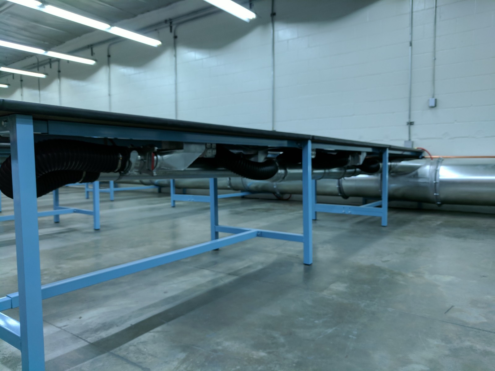 Ducting under a grinding table in a manufacturing facility.