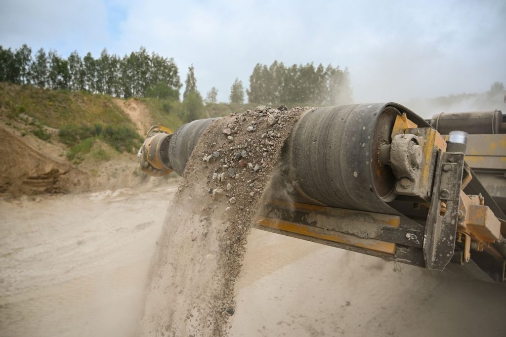 Close-up of an industrial conveyor belt carrying crushed gravel