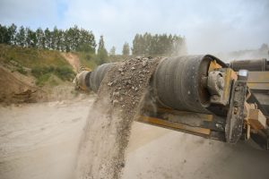 Close-up of an industrial conveyor belt carrying crushed gravel