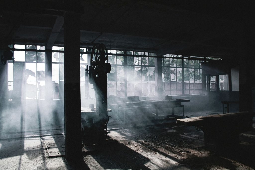 Dust hanging in the air inside an industrial plant, lit by shafts of light from high windows