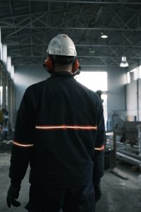 Worker in full safety gear standing on the floor of a modern industrial plant