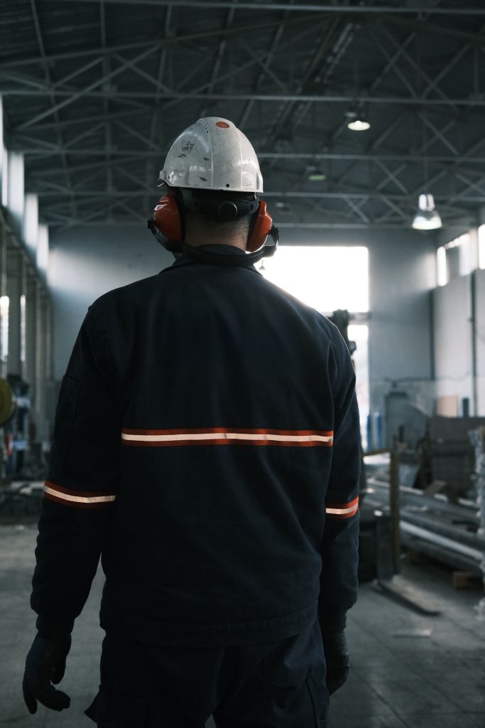 Worker in full safety gear standing on the floor of a modern industrial plant