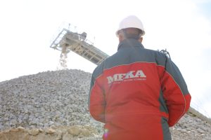 Worker in a quarry observing a running conveyor